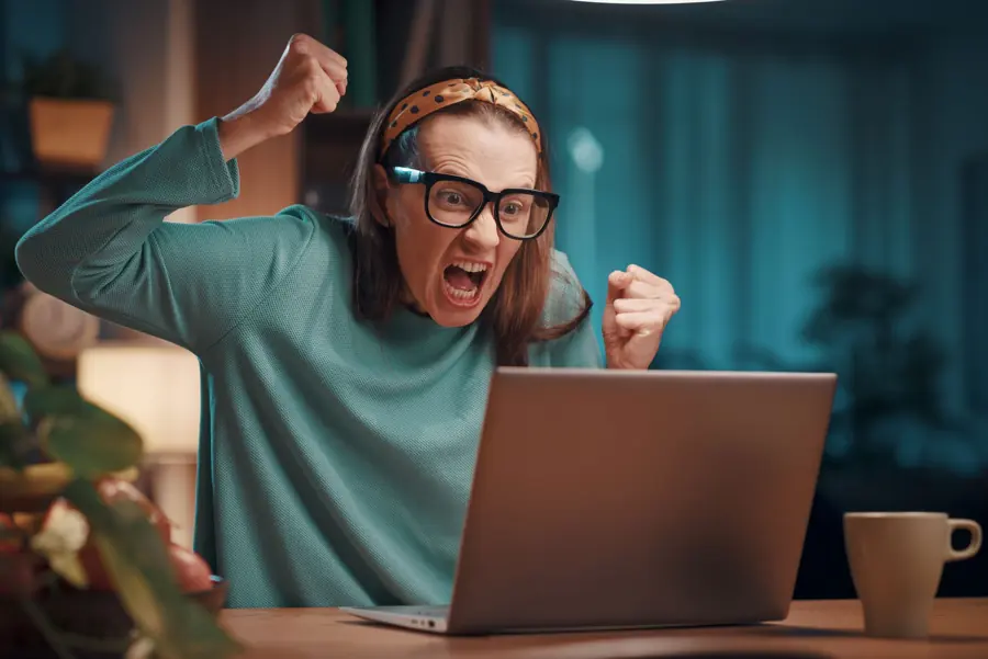 Frau mit Brille überrascht vor dem Laptop
